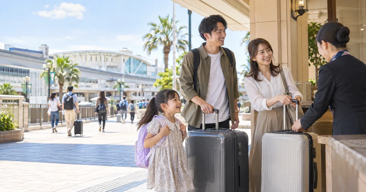 舞浜駅近くで、大型スーツケースをホテルスタッフに預ける家族。